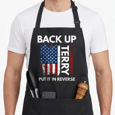 Reverse 4th of july apron - Distressed USA flag with BACK UP TERRY PUT IT IN REVERSE text — shown on a black cotton canvas apron against a white background