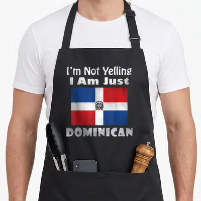 Yelling rummy apron - Distressed Dominican flag with I'm Not Yelling I Am Just DOMINICAN text — shown on a black cotton canvas apron against a white background