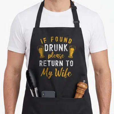 Return wife apron - Distressed yellow and white text reading If Found Drunk Return To My Wife flanked by two beer — shown on a black cotton canvas apron against a white background