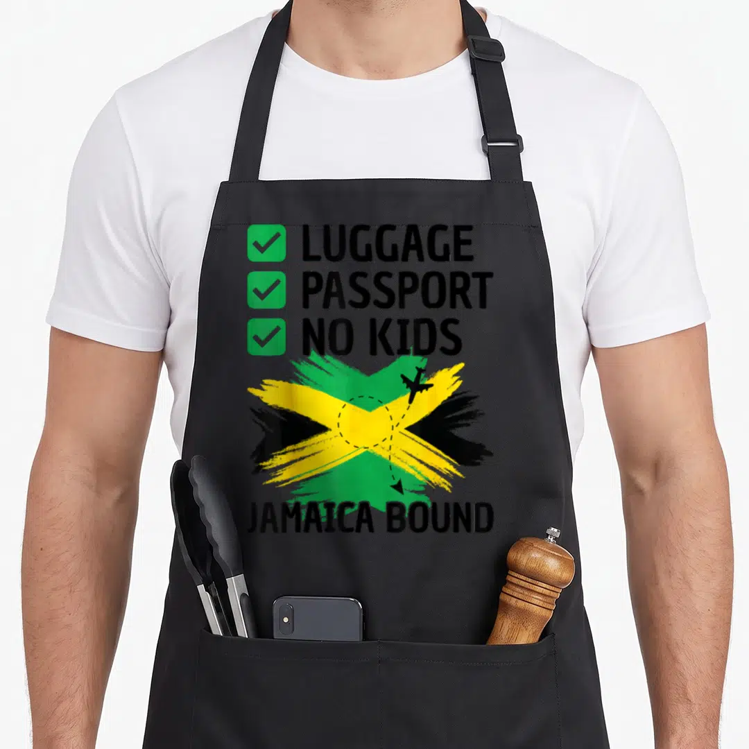 Jamaican travel aprons - Checklist reading Luggage Passport No Kids above brush stroke Jamaican flag with airplane — shown on a black cotton canvas apron against a white background