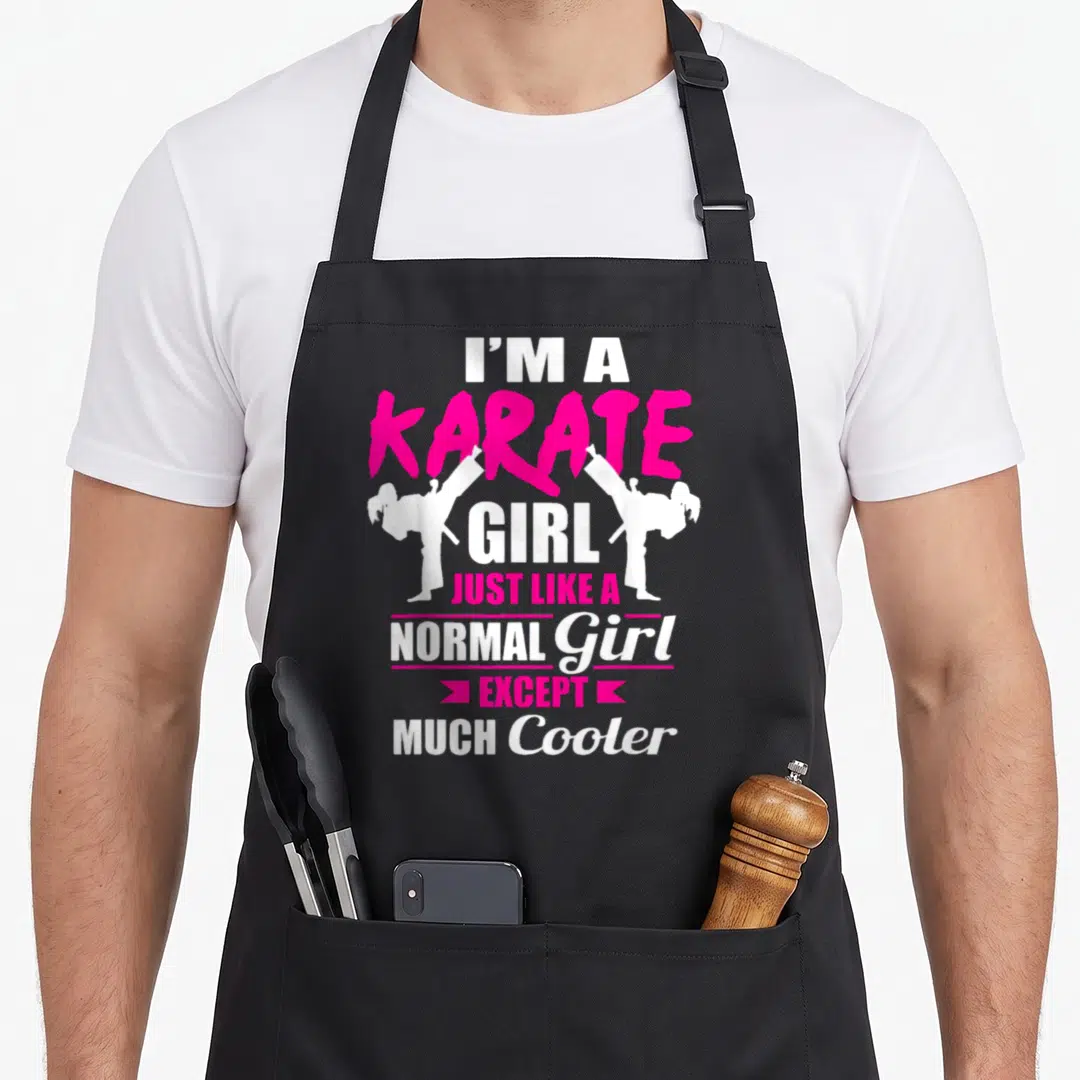 But karate apron - Pink and white text I'M A KARATE GIRL with two white silhouettes of girls doing high kicks — shown on a black cotton canvas apron against a white background