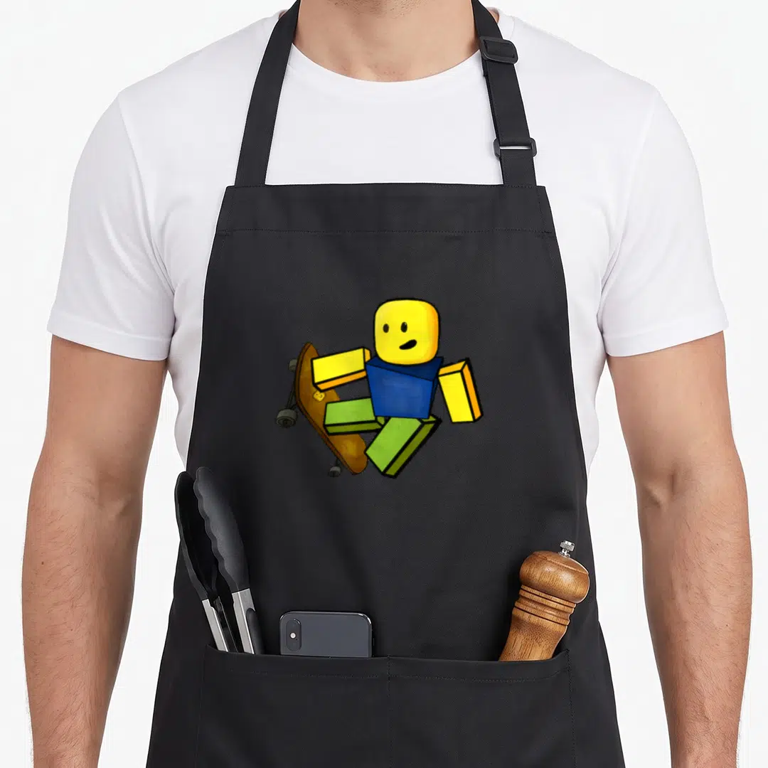 Blox gaming apron - Blocky character with yellow head blue body green legs on brown skateboard — shown on a black cotton canvas apron against a white background