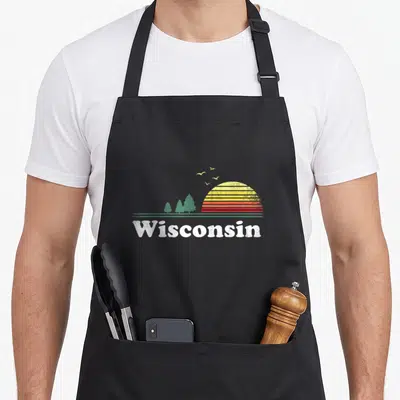 State wisconsin apron - Retro striped sun over green pines with white Wisconsin text — shown on a black cotton canvas apron against a white background