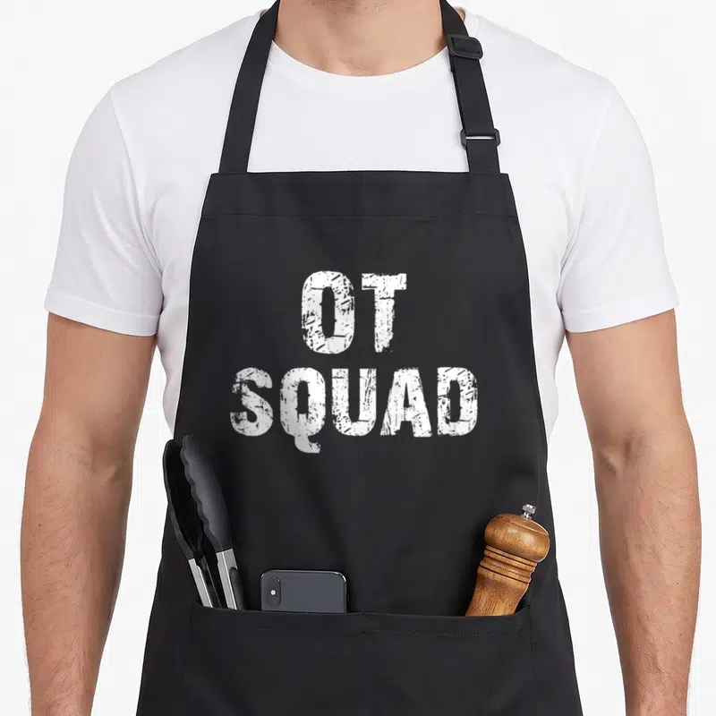 Squad ot apron - White distressed typography reading OT SQUAD stacked on two lines — shown on a black cotton canvas apron against a white background