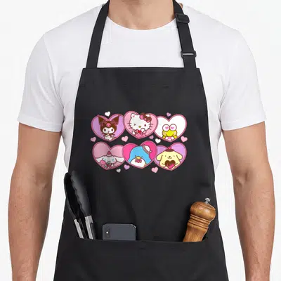 Character valentine's day apron - Six cartoon characters inside pink hearts with scattered small hearts on white — shown on a black cotton canvas apron against a white background