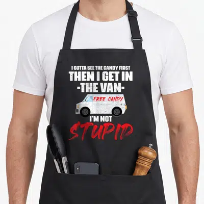 Van candy aprons - Stacked text reading I Gotta See The Candy First around a cartoon van with Free Candy written in red — shown on a black cotton canvas apron against a white background