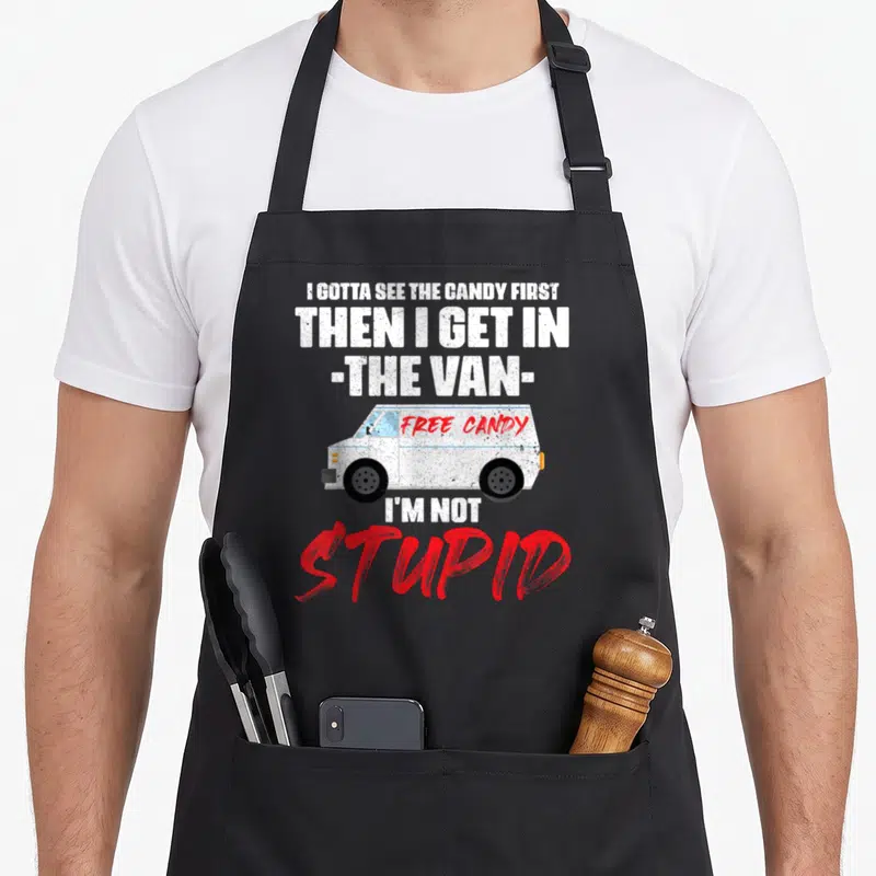 Van candy aprons - Stacked text reading I Gotta See The Candy First around a cartoon van with Free Candy written in red — shown on a black cotton canvas apron against a white background