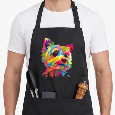 Colorful yorkie apron - Multicolored cartoon Yorkshire Terrier head in pink, yellow, blue, green, and orange pop art — shown on a black cotton canvas apron against a white background