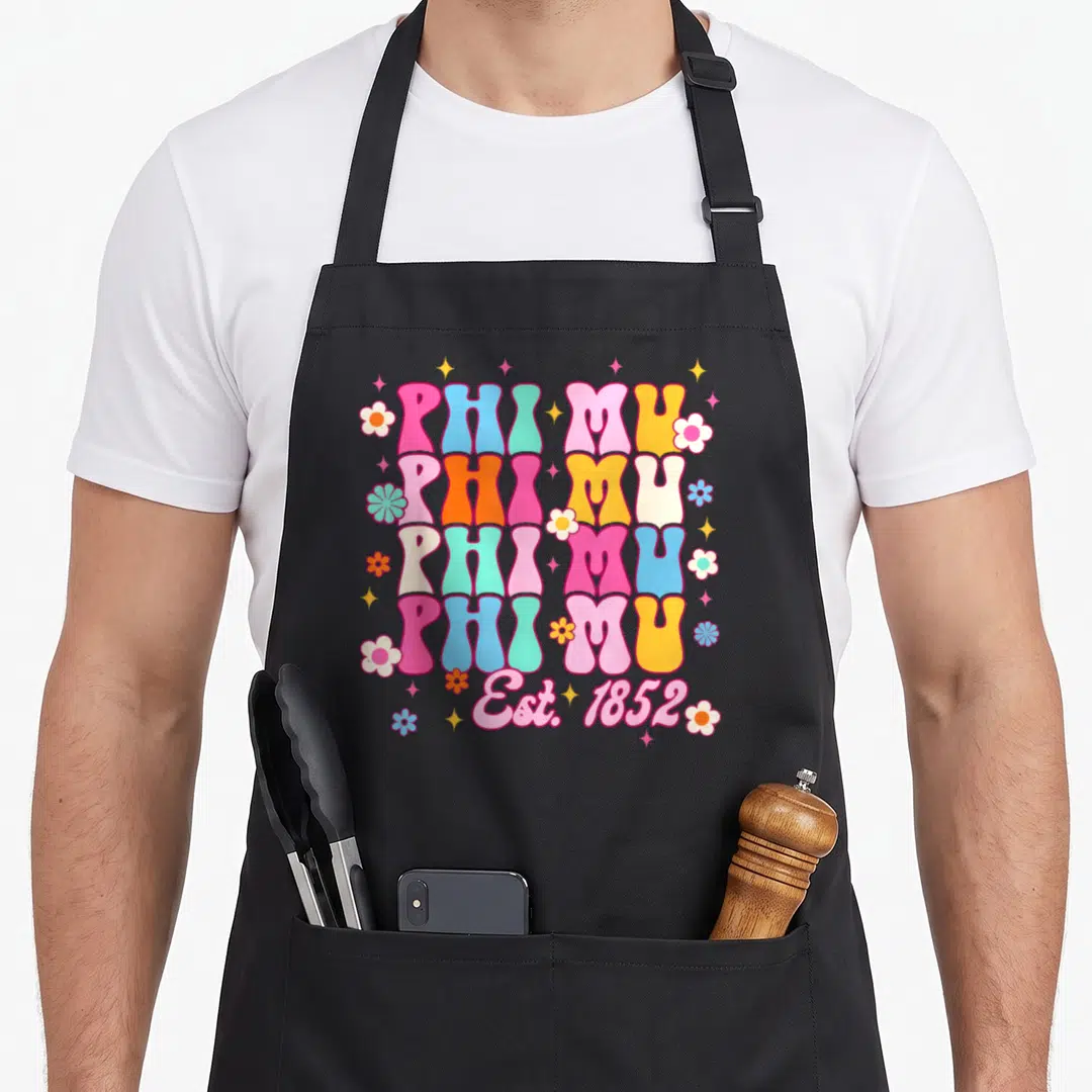 Phi mu aprons - Retro stacked PHI MU text with flowers and stars in pink blue yellow and orange — shown on a black cotton canvas apron against a white background