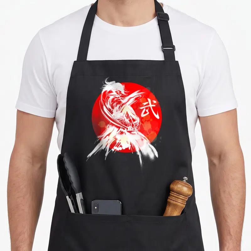 Calligraphy japan apron - White watercolor samurai wielding a katana over a red circle next to a kanji character — shown on a black cotton canvas apron against a white background