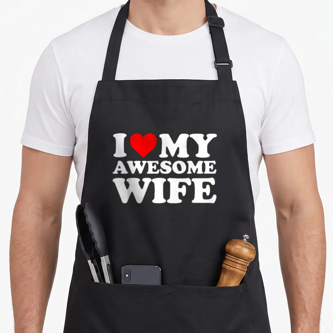 Cool wife apron - White I MY AWESOME WIFE text with red heart between first two letters — shown on a black cotton canvas apron against a white background