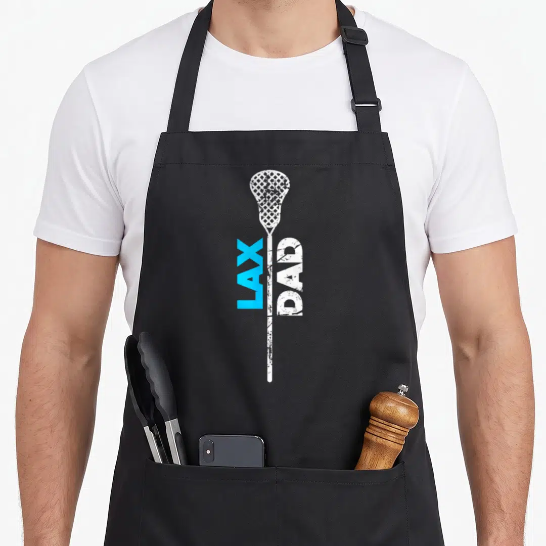 Lax lacrosse dad apron - Vertical white lacrosse stick with distressed LAX in blue and DAD in white text — shown on a black cotton canvas apron against a white background