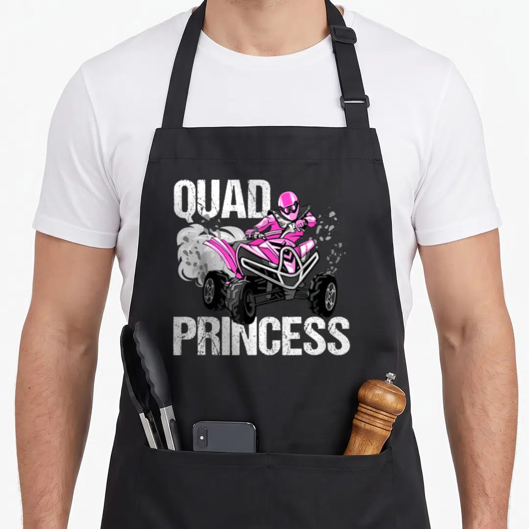 Quad princess apron - Pink ATV rider with white QUAD PRINCESS text and smoke clouds — shown on a black cotton canvas apron against a white background