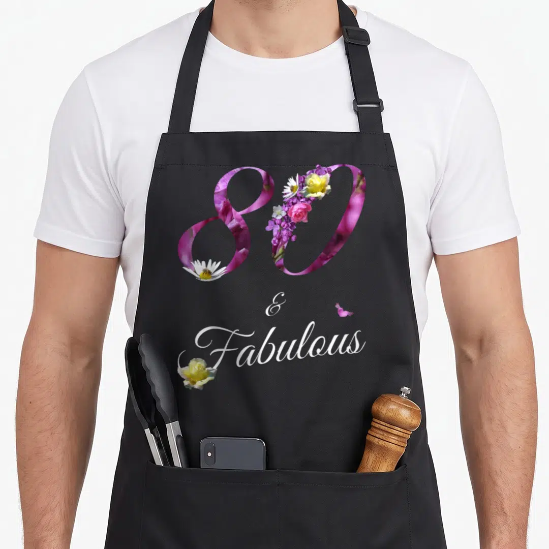Fabulous floral aprons - Number 80 filled with pink yellow purple flowers above Fabulous script text — shown on a black cotton canvas apron against a white background