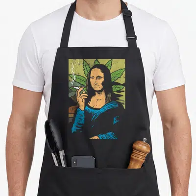 Mona smoking apron - Cartoon Mona Lisa holding joint with green cannabis leaves background — shown on a black cotton canvas apron against a white background
