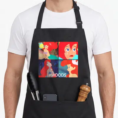 Mood mermaid apron - Four panel grid of Ariel expressions with #MOODS text in red blue teal and yellow — shown on a black cotton canvas apron against a white background