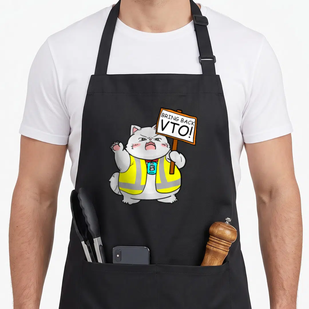 Vto kitten apron - Cartoon grey cat in yellow safety vest holding a white sign with text BRING BACK VTO — shown on a black cotton canvas apron against a white background