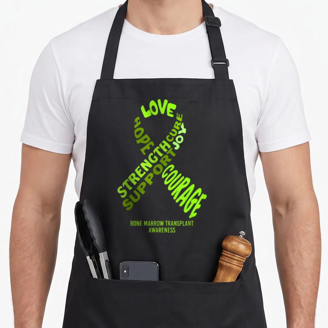 Bone ribbon apron - Ribbon shape formed by words Love Hope Strength Support Cure Joy Courage in lime and olive green — shown on a black cotton canvas apron against a white background