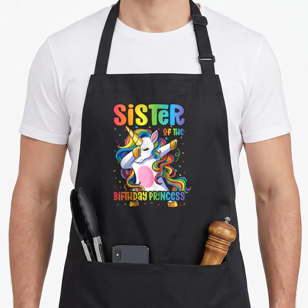 Sister birthday dabbing princess apron - Dabbing rainbow unicorn with SiSTER OF THE BIRTHDAY PRINCESS text and confetti — shown on a black cotton canvas apron against a white background