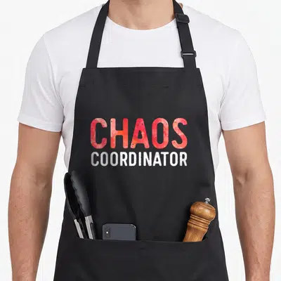 Cute chao coordinator apron - Red and white stacked text reading CHAOS COORDINATOR in distressed font — shown on a black cotton canvas apron against a white background