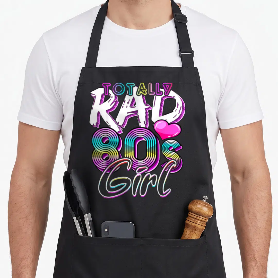 Totally 80s apron - Stacked totally ally rad 80s girl text with striped neon numbers and pink heart — shown on a black cotton canvas apron against a white background