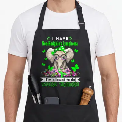 Non lymphoma awareness apron - Cartoon elephant with green bow and flowers holding ribbon, I Have Non-Hodgkin's — shown on a black cotton canvas apron against a white background