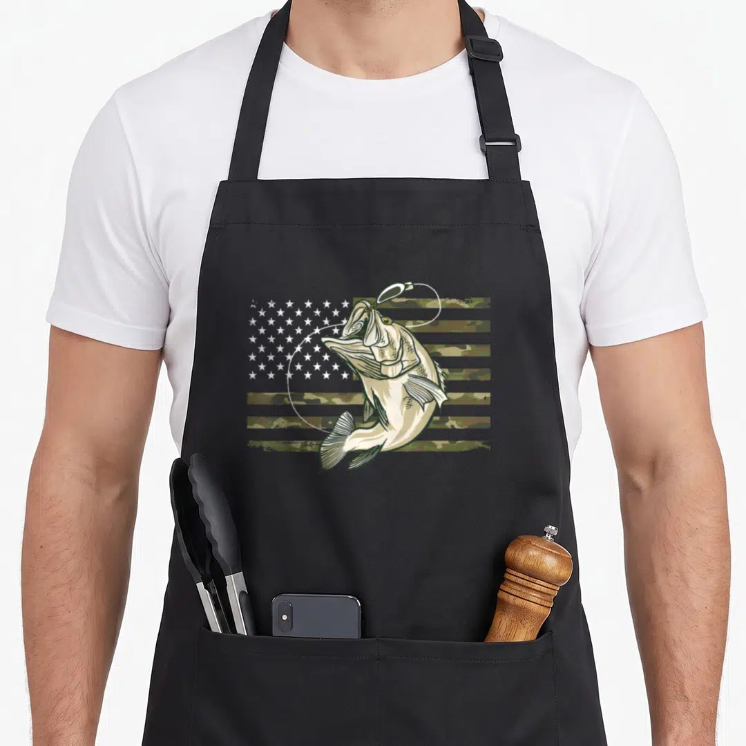 Camouflage american flag apron - Cartoon bass jumping with lure in mouth in front of camo patterned US flag — shown on a black cotton canvas apron against a white background