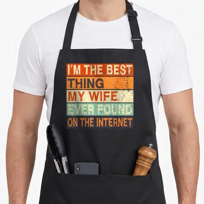Dating husband wife aprons - Five horizontal stripes in orange red beige and blue with distressed white and dark text — shown on a black cotton canvas apron against a white background
