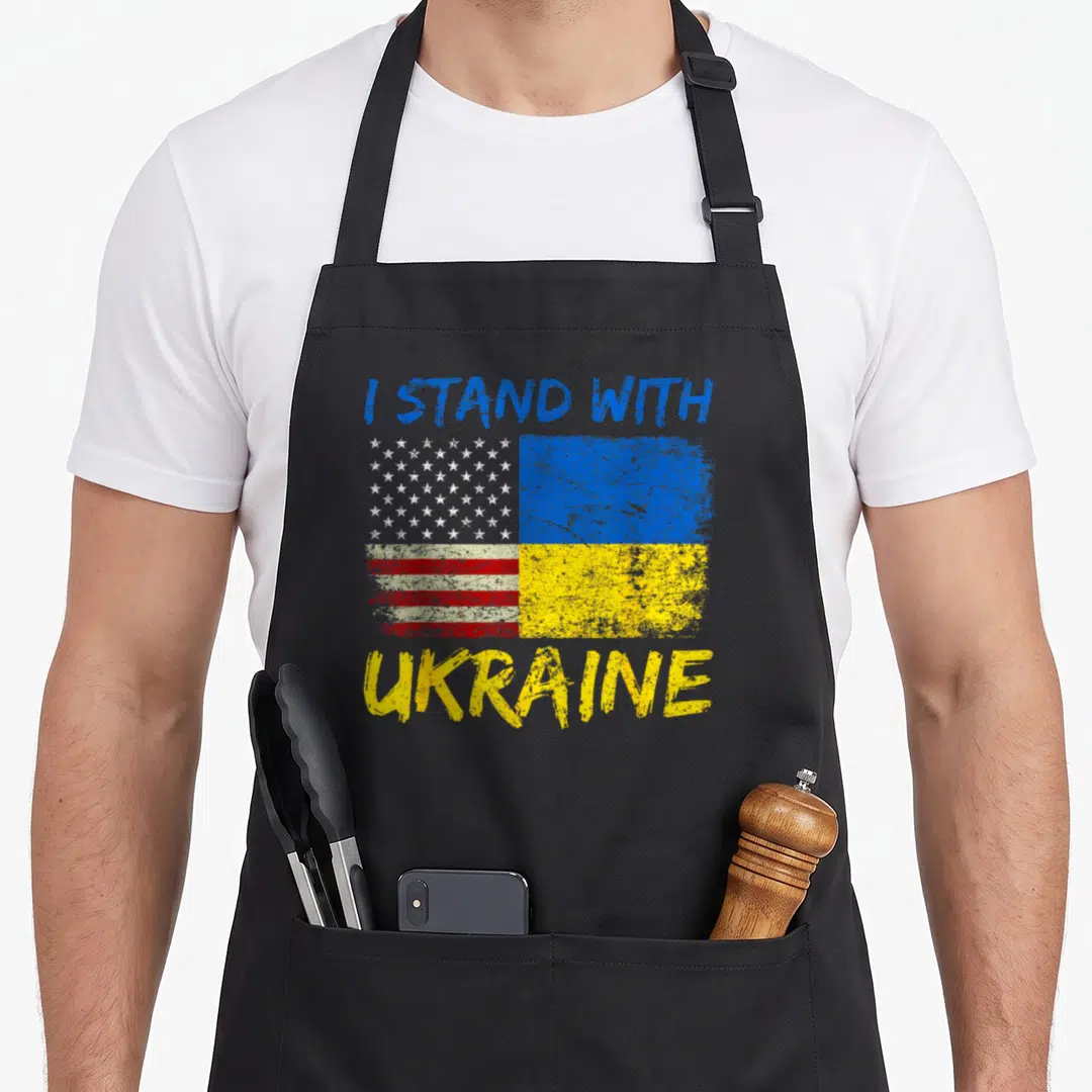 Flag pride ukrainian aprons - Distressed split flag graphic with white stars red stripes blue yellow blocks and I Stand — shown on a black cotton canvas apron against a white background
