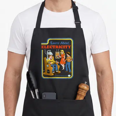 Steven crazy robin man apron - Boy in electric chair with Learn About Electricity text in retro blue yellow red orange — shown on a black cotton canvas apron against a white background