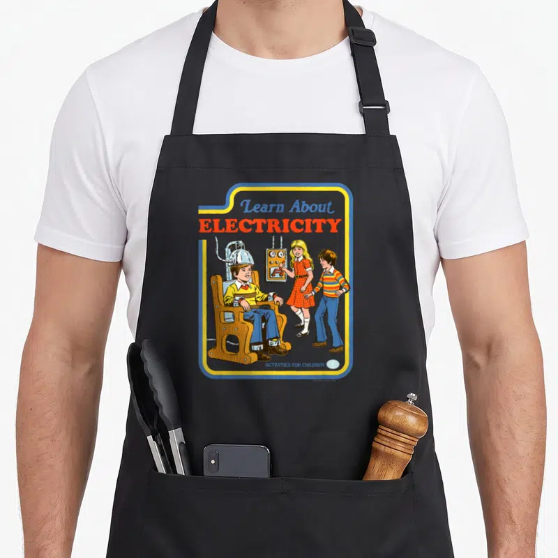 Steven crazy robin man apron - Boy in electric chair with Learn About Electricity text in retro blue yellow red orange — shown on a black cotton canvas apron against a white background