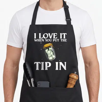 Mixologist bartending bartender apron - Cartoon tip jar filled with cash surrounded by sparkles and white pun lettering — shown on a black cotton canvas apron against a white background