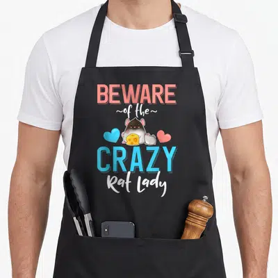Beware pet apron - Cartoon rat holding cheese between blue and coral hearts with text — shown on a black cotton canvas apron against a white background