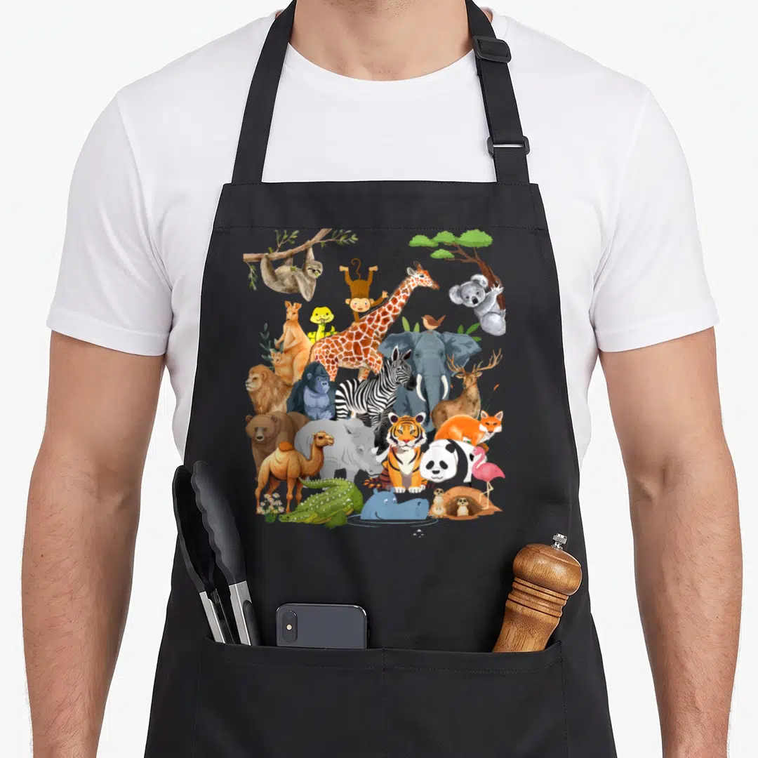 Wildlife animal apron - Cartoon cluster of 22 zoo animals including tiger, elephant, giraffe, sloth, and koala framed — shown on a black cotton canvas apron against a white background