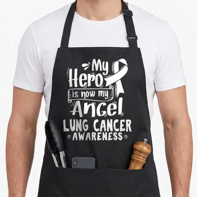 Nsclc lung cancer awareness apron - White My Hero is now my Angel text and ribbon on black bib — shown on a black cotton canvas apron against a white background