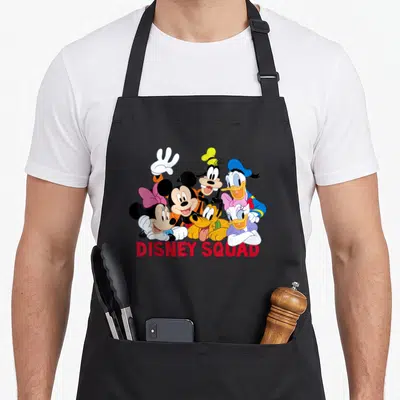 Squad friends apron - Cluster of cartoon characters above red DISNEY SQUAD text — shown on a black cotton canvas apron against a white background