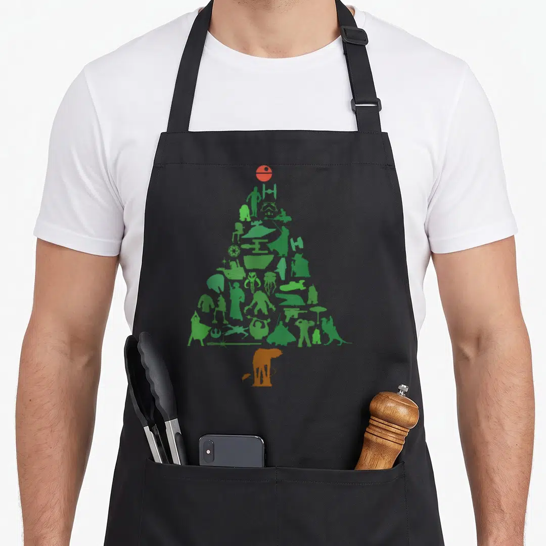 Holiday christmas tree apron - Green and orange Star Wars silhouettes arranged in a Christmas tree shape on black fabric — shown on a black cotton canvas apron against a white background