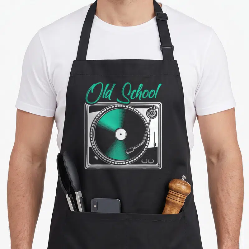 Deejay vinyl apron - Old School teal script above white turntable line art with grey and teal record — shown on a black cotton canvas apron against a white background
