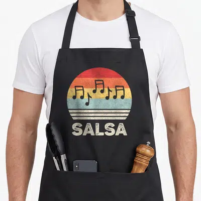Dancing salsa apron - Five musical notes on red orange yellow light blue white striped circle with SALSA text below — shown on a black cotton canvas apron against a white background