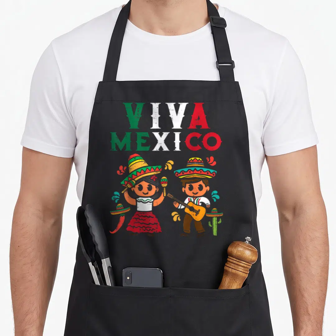 Maracas mexico apron - VIVA MEXICO text above cartoon couple with maracas, guitar, chili, and cactus in green white red — shown on a black cotton canvas apron against a white background