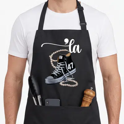 Assignment presidents apron - Black sneaker with la script and 47 number draped in cream pearls — shown on a black cotton canvas apron against a white background