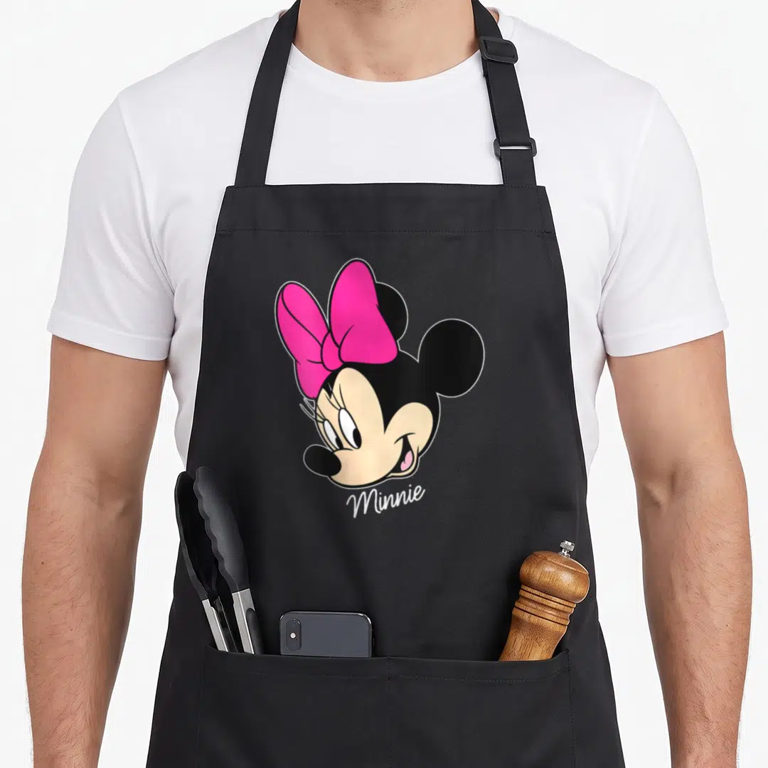 Vintage face friends apron - Cartoon Minnie Mouse head with pink bow and beige face, text Minnie below — shown on a black cotton canvas apron against a white background