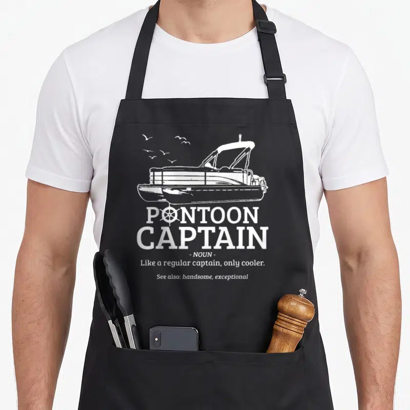Pontoon captain apron - White pontoon boat with flying birds and definition text like a regular captain only cooler — shown on a black cotton canvas apron against a white background
