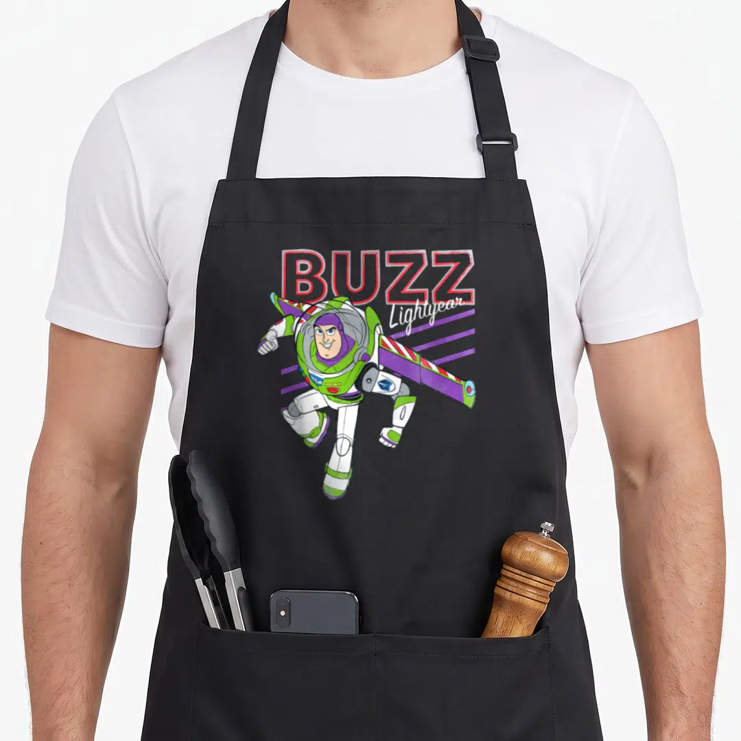 Cute camping apron - Buzz Lightyear flying in white and green suit with red BUZZ text above — shown on a black cotton canvas apron against a white background