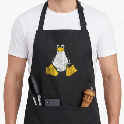 Mascot nerd apron - Cartoon penguin sitting above the word Linux in distressed black and yellow print — shown on a black cotton canvas apron against a white background