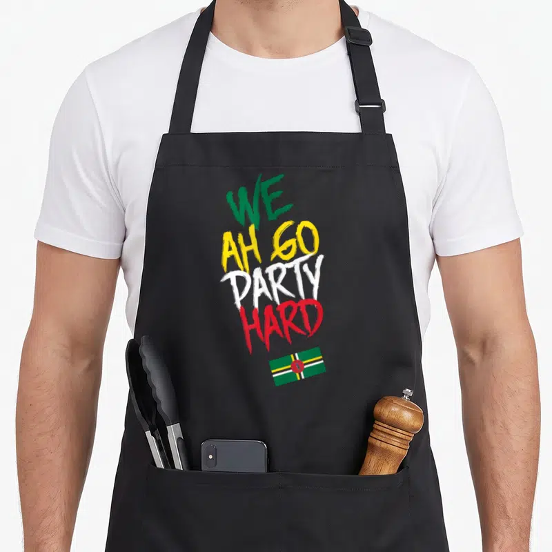 Hard carnival apron - Stacked brush text We Ah Go Party Hard above Dominica flag — shown on a black cotton canvas apron against a white background