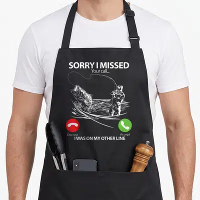Line fishing aprons - Fisherman catching bass with missed call text and red green buttons — shown on a black cotton canvas apron against a white background