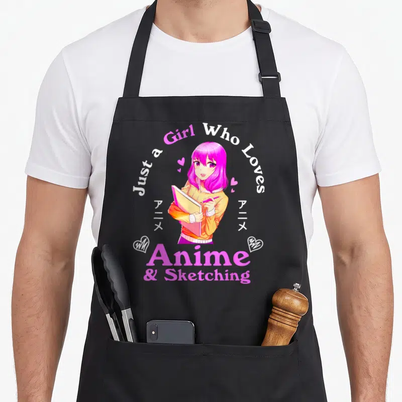 Sketching anime apron for cooking - Pink haired anime girl holding sketchbook with arched text and white hearts — shown on a black cotton canvas apron against a white background