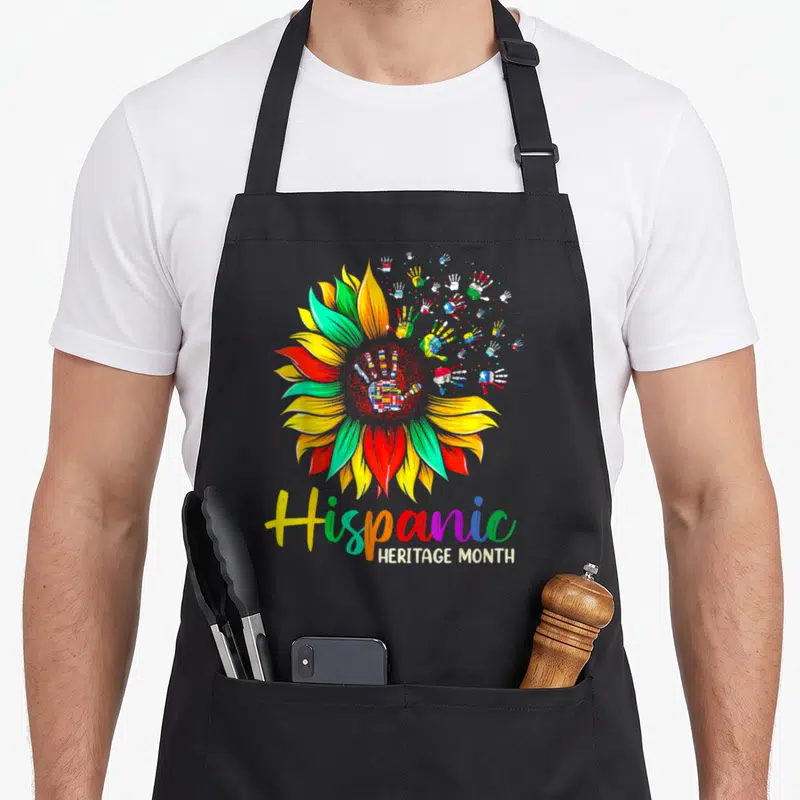 Sunflower country apron - Colorful sunflower with painted flag hands and Hispanic Heritage Month text — shown on a black cotton canvas apron against a white background