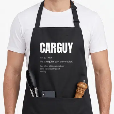 Definition car apron - White CARGUY dictionary definition text stacked on black fabric background — shown on a black cotton canvas apron against a white background